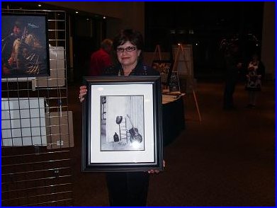 E G Kight holding one of her photographs at the silent auction